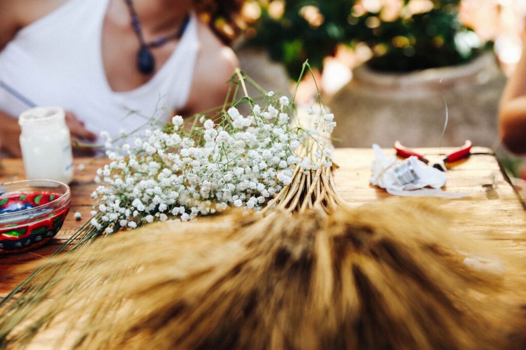 Handcrafted floral arrangement featuring baby's breath and wheat on a rustic table.